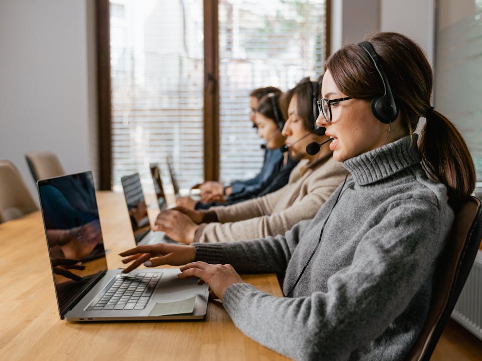 Equipo de agentes con audífonos y laptops gestionando citas médicas