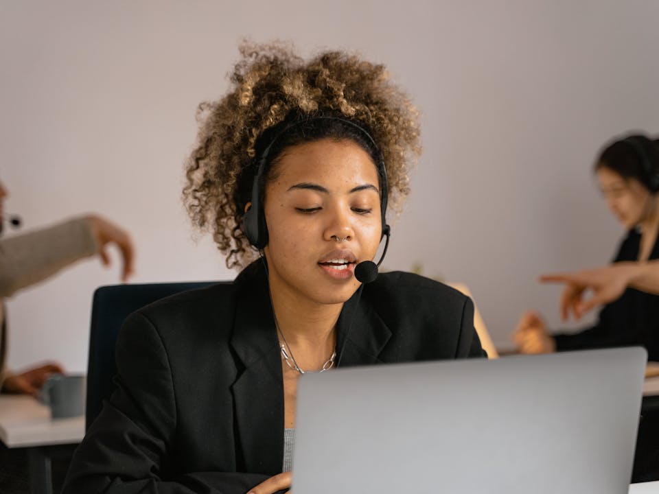 Agente de soporte técnico con audífonos y laptop atendiendo clientes de telecomunicaciones