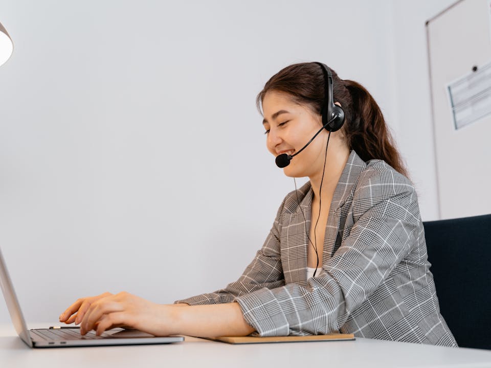 Agente de atención a clientes con audífonos y laptop gestionando campañas de mensajería