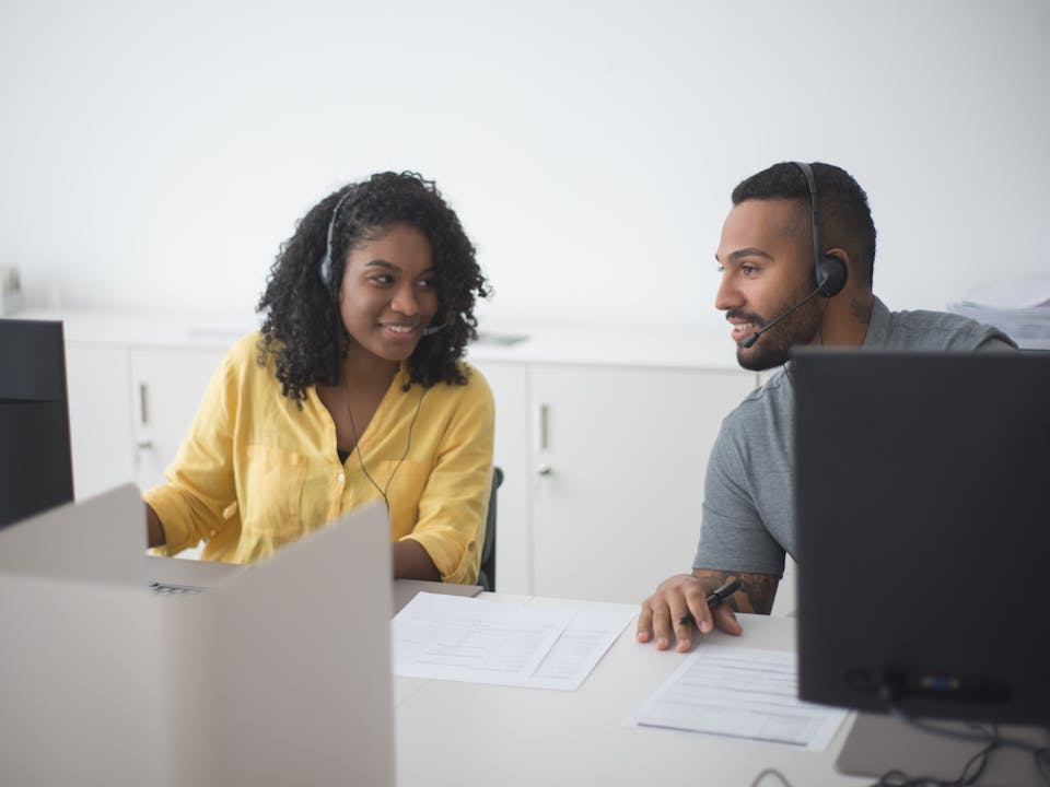 Agentes de ventas automotriz con headsets en oficina de concesionario