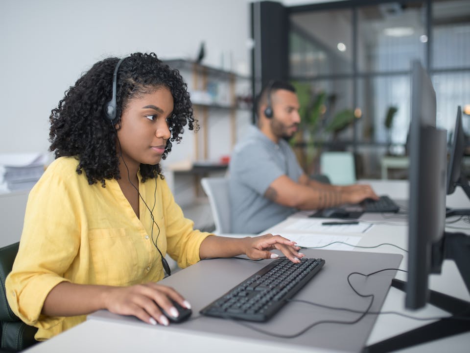 Equipo de agentes en contact center trabajando con audífonos y computadoras